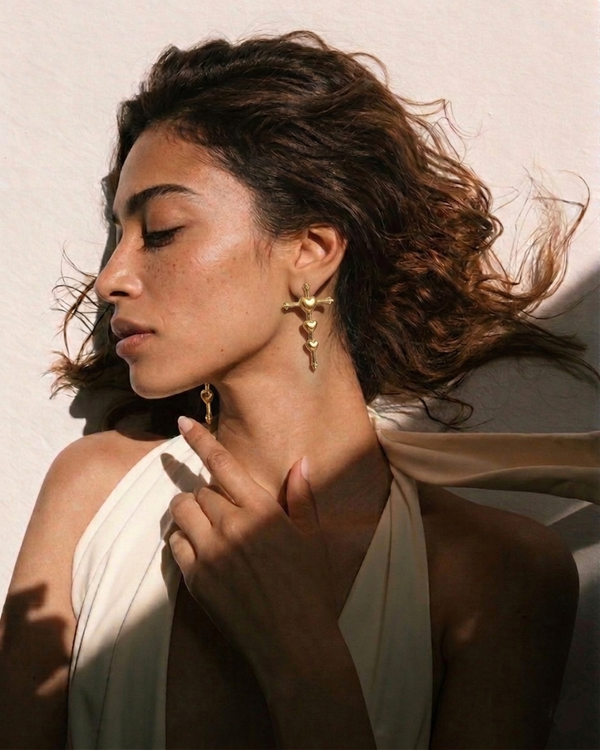 Woman wearing gold earrings with a neutral background