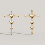 Load image into Gallery viewer, Pair of gold earrings with heart and cross design on a light gray background